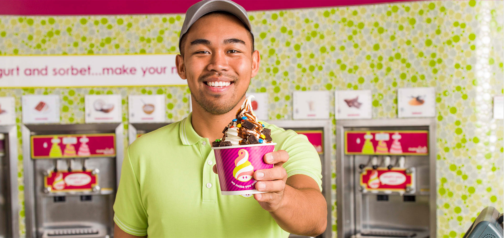 A team member holding up a cup of frozen yogurt