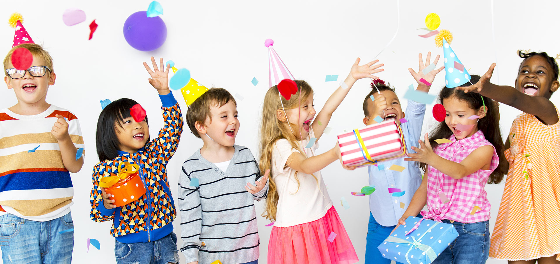 Several children celebrating with birthday hats and confetti
